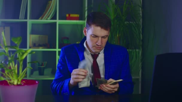Молодий бізнесмен з грошима в офісі. Чоловік-підприємець рахує доларові купюри, сидячи за столом на сучасному робочому місці . — стокове відео