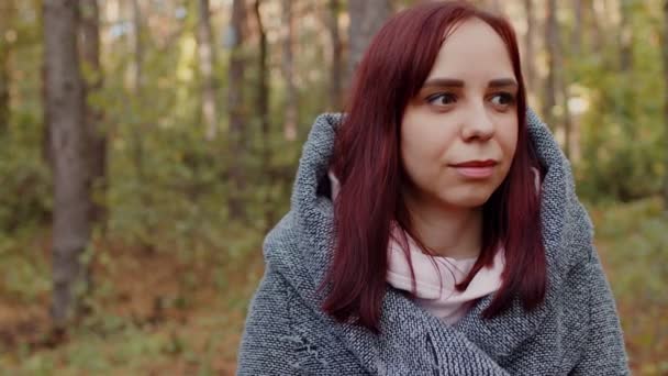 Primer plano retrato de mujer atractiva. Sonriente morena segura de sí misma bonita. Una mujer joven y atractiva, soñando mirando hacia otro lado en el fondo de un bosque otoñal. Una mujer confiada y soñadora — Vídeos de Stock