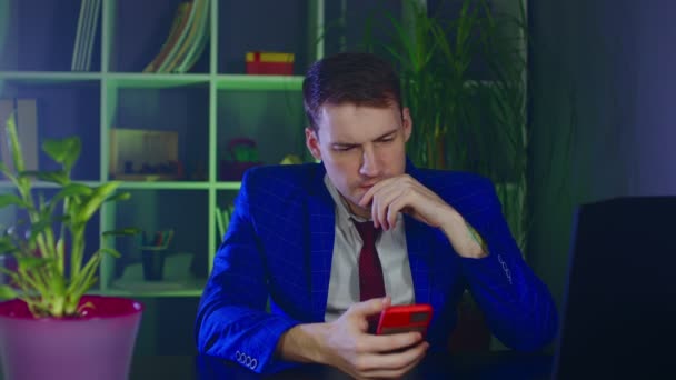 Розумний бізнесмен використовує мобільний телефон на сучасному робочому місці. Молодий чоловік переглядає смартфон, сидячи в офісі . — стокове відео