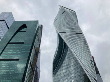 Camdan duvarları olan modern gökdelen cephesi. Şehir merkezindeki bulutlu gökyüzüne karşı cam duvarları olan çağdaş yüksek gökdelenden