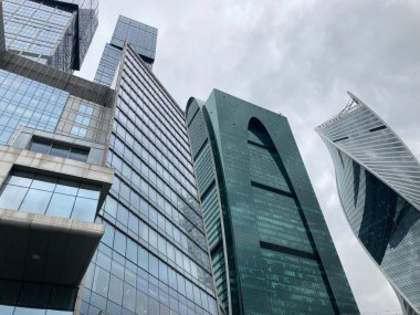 Camdan duvarları olan modern gökdelen cephesi. Şehir merkezindeki bulutlu gökyüzüne karşı cam duvarları olan çağdaş yüksek gökdelenden