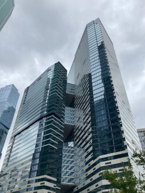 Camdan duvarları olan modern gökdelen cephesi. Şehir merkezindeki bulutlu gökyüzüne karşı cam duvarları olan çağdaş yüksek gökdelenden