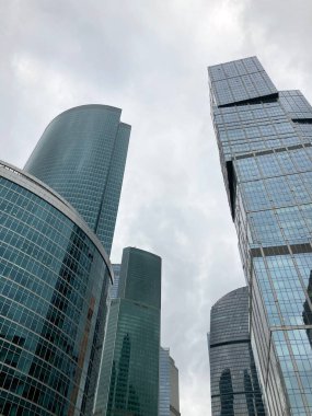 Camdan duvarları olan modern gökdelen cephesi. Şehir merkezindeki bulutlu gökyüzüne karşı cam duvarları olan çağdaş yüksek gökdelenden