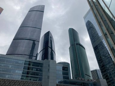 Camdan duvarları olan modern gökdelen cephesi. Şehir merkezindeki bulutlu gökyüzüne karşı cam duvarları olan çağdaş yüksek gökdelenden