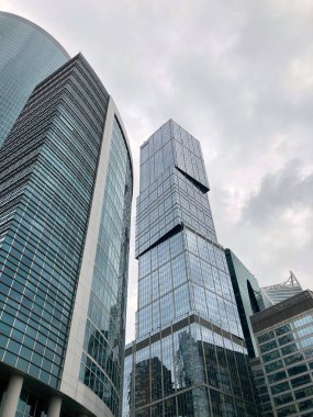 Camdan duvarları olan modern gökdelen cephesi. Şehir merkezindeki bulutlu gökyüzüne karşı cam duvarları olan çağdaş yüksek gökdelenden