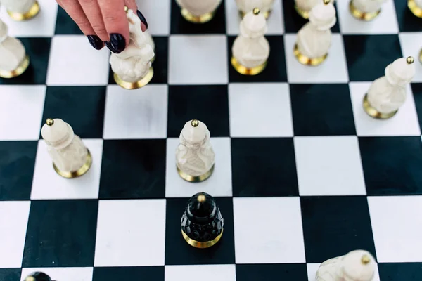 Selektivní zaměření krásných šachovnic na šachovnici. Detailní záběr části těla nerozpoznatelné ženy hrající v deskové hře na ulici — Stock fotografie