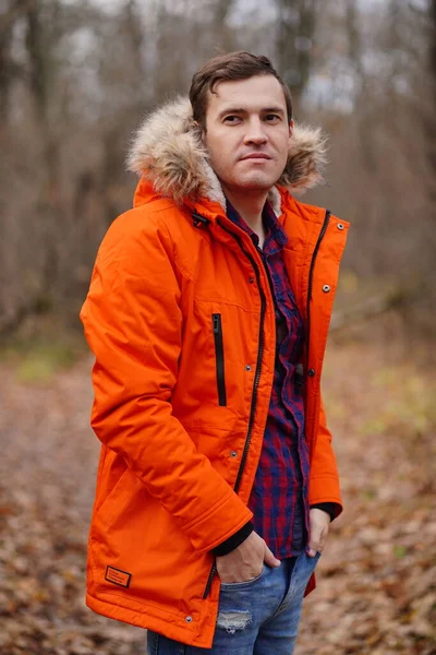 Egy narancssárga dzsekis fiatalember portréja az őszi erdőben. Felnőtt férfi pózol a friss levegőn az őszi szezonban. — Stock Fotó