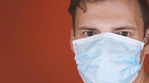 Человек в медицинской маске на лице на оранжевом фоне. Эпидемия коронавируса . — стоковое фото