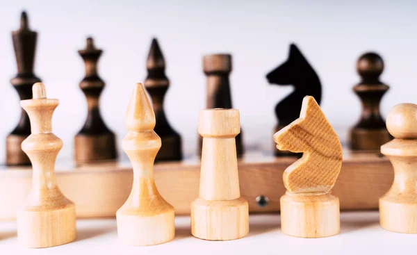 Bílé a černé dřevěné figurky na šachovnici. Šachovnice nastavená během hry na šedém pozadí. — Stock fotografie