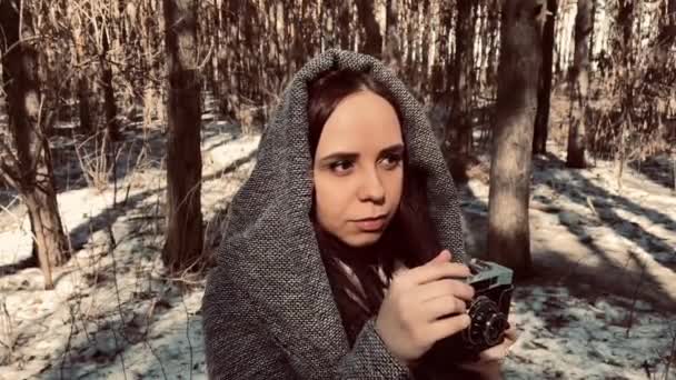 Jonge vrouw in grijze jas fotografeert op oude fotocamera in het bos. Mooie vrouw het nemen van foto 's met oude camera in het vroege voorjaar. — Stockvideo