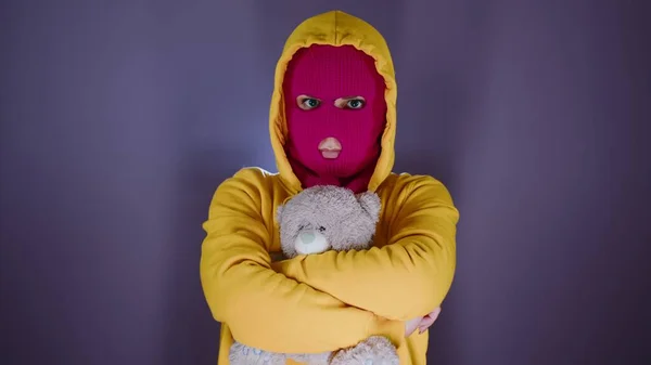 Młoda kobieta w różowej kominiarce z misiaczkiem. Hooligan w masce z pluszową zabawką w rękach. — Zdjęcie stockowe