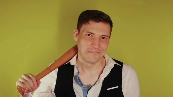 Man on strict face posing with wooden bat. A man in a business strict elegant suit with a wooden bat in his hands. Aggressive business — Stock Photo, Image