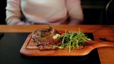 Tahta tahtada sebzeli leziz biftek. Tanınmayan kişi ete sos serper. Yiyecek konsepti.