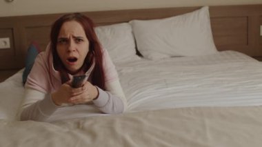 Genç bir kadın yatağa uzanıyor, televizyon seyrediyor ve esniyor. Rahatlamış bir kadın diziyi izlerken esniyor ve uzaktan kumandayla kanal değiştiriyor..