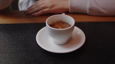 Masada taze demlenmiş kahve. Tanınmayan bir kadın restoranda kaşıkla espresso karıştırıyor. Kapat..