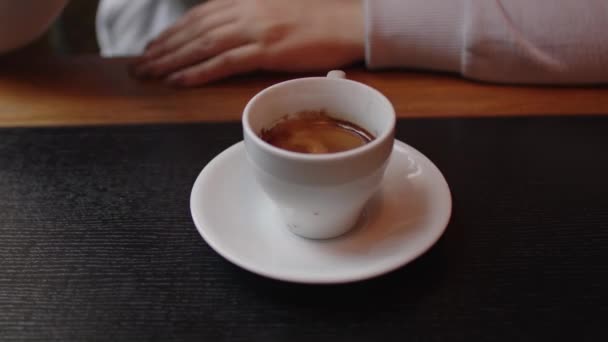 Café recién hecho en la mesa. Mujer irreconocible revuelve espresso con cuchara en el restaurante. De cerca.. — Vídeos de Stock