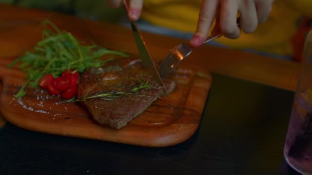 Succulent steak with vegetables on wooden board. Unrecognizable man cuts off piece and eats. Food concept. — Stock Video