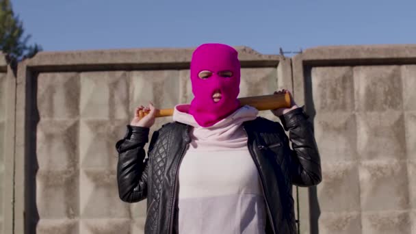 Jeune femme en cagoule rose avec batte de baseball. Hooligan en masque avec chauve-souris dans les mains. — Video