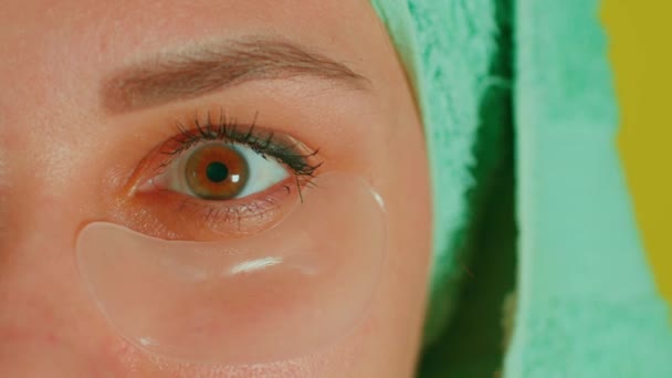 Young woman with towel on head and patches under her eyes. Adult female courting of her face in domestic conditions. Concept of fighting wrinkles and dark circles under eyes. Close up — Stock Video