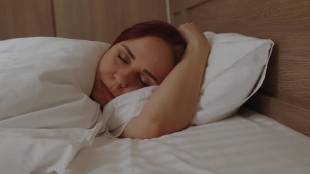 Junge Frau liegt auf Kopfkissen unter Decke und schläft morgens im Bett. Schlafendes Weibchen ruht am Wochenende am frühen Morgen. — Stockvideo