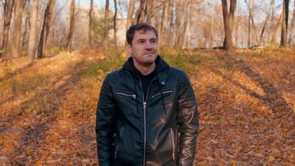 Egy fiatal jóképű férfi portréja alkalmi ruhában az őszi erdő sárgás fái ellen.. — Stock videók