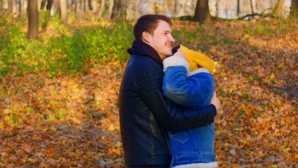 秋の森の中でアウトドアを受け入れる幸せなカップル。男抱擁彼の女性を柔らかくし、愛とキス. — ストック動画