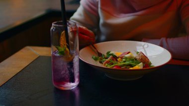 Beyaz tabakta iştah açıcı salata. Tanınmayan bir kadın çatalla yemek seçiyor. Kapat..