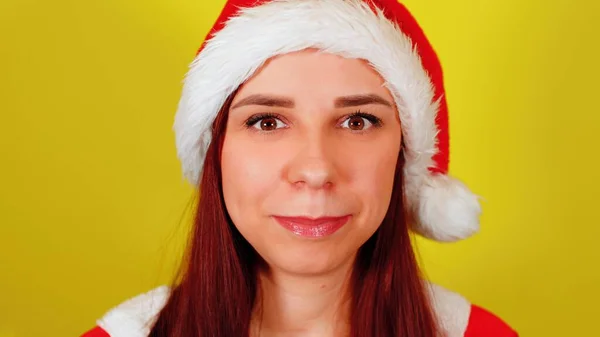 Mulher em traje de Papai Noel em fundo amarelo. Bonita fêmea de chapéu de Natal olhando para a câmera e sorrindo. — Fotografia de Stock