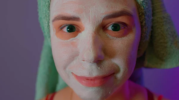Młoda kobieta z ręcznikiem na głowie i maską na twarzy po zabiegach pod prysznicem. Kobieta zalecająca się do twarzy maską kosmetyczną. Pojęcie spa, pielęgnacji skóry i naturalnego piękna w warunkach domowych. — Zdjęcie stockowe