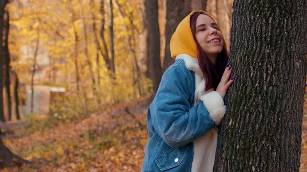 Egy fiatal nő megöleli a fát az őszi erdőben. Gyönyörű női ölelések gyengéden törzs fa őszi szezonban. — Stock Fotó