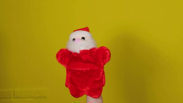 Peluche de marionnettes douces de Père Noël à portée de main. Marionnette du Père Noël sur fond jaune. Ferme là. Concept de spectacle de marionnettes et fêtes de fin d'année. — Video
