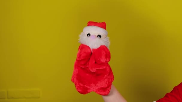 М'яка маріонеткова іграшка Санта-Клауса під рукою. Санта-Клаус лялька на жовтому тлі. Близько. Концепція маріонеткового шоу та новорічних свят . — стокове відео