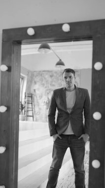 Yakışıklı bir adam aynaya bakar. Modern bir yatak odasındaki aynada genç bir erkeğin yan görüntüsü.