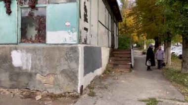 Novocherkassk, Rusya 10 Ekim 2021: Yaşlı kadınlar eski sokakta konuşuyor. Büyükanneler evin yanında durup sohbet ediyorlar..