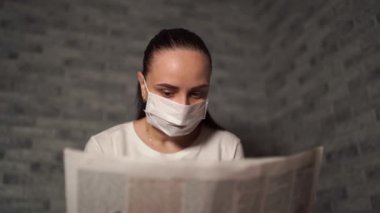 Tıbbi maskeli bir kadın koronavirüs haberini gazeteden duymuş. Coronavirüs Salgını.