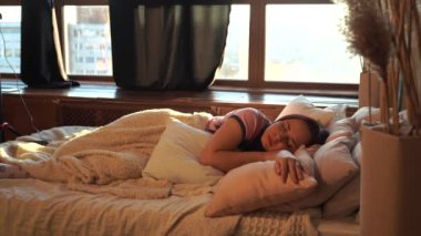 Sabahları pijamalı güzel bir kadın yatakta dinleniyor. Büyüleyici kadın yastık yığınında uyuyor..