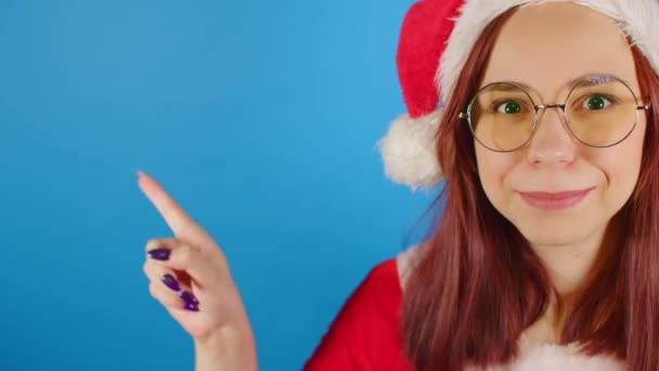 Vrouw Kerstman Kostuum Bril Wijst Vingerruimte Voor Tekst Blauwe Achtergrond — Stockvideo