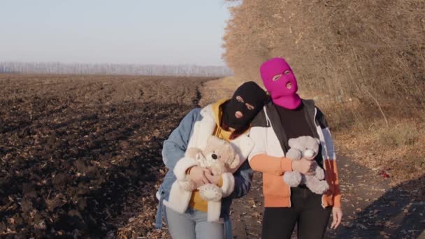 Mujeres en pasamontañas con osos de peluche al aire libre. Gamberros en máscaras con peluches en las manos. — Vídeos de Stock