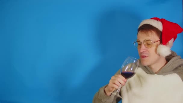 Man Santa Hat Eyeglasses Drinks Red Wine Blue Background Space — Stock Video