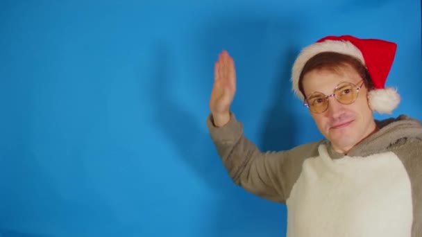 Man Met Kerstmuts Bril Zwaaiend Met Zijn Hand Kijkend Naar — Stockvideo