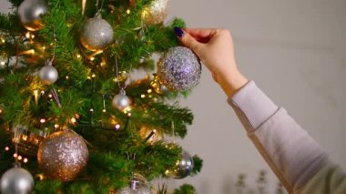 Noel ağacına parlak mücevherler asan bir kadın. Evdeki Noel kutlaması için hazırlanırken köknar dalını gümüşle süsleyen isimsiz bir kadın.
