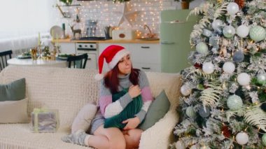Noel ağacına hayran bir kadın. Yeni yıl şapkalı güzel bir esmer, Noel ağacına hayran. Genç bir bayan güzel dekore edilmiş bir Noel ağacına bakıyor.