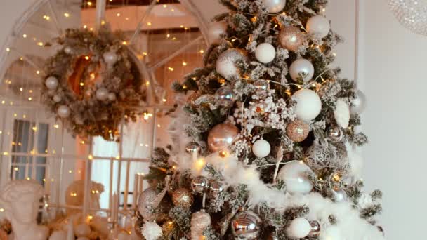 Árvore de Natal com diferentes brinquedos de Natal e guirlanda brilhante no quarto. Espumante árvore conífera decorada com adornos para criar humor festivo durante as férias. — Vídeo de Stock