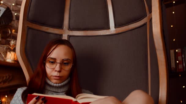 Young woman in glasses reading book. Interested student in eyeglasses reads book, preparing for educational lessons. — Video Stock