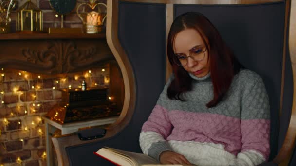 Gözlüklü genç kadın kitap okuyor. Gözlükle ilgilenen öğrenci kitap okuyor, eğitici derslere hazırlanıyor.. — Stok video