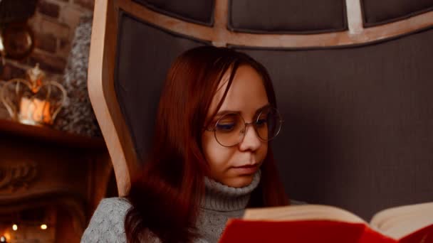 Ung kvinna i glasögonbok. Intresserad student i glasögon läser bok, förbereder sig för pedagogiska lektioner. Närbild. — Stockvideo