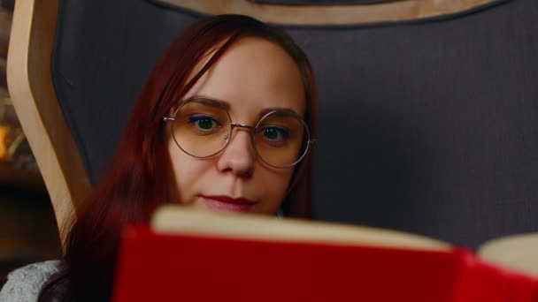 Jovem mulher de óculos livro de leitura. Estudante interessado em óculos lê livro, preparando-se para aulas educacionais. Fechar. — Vídeo de Stock