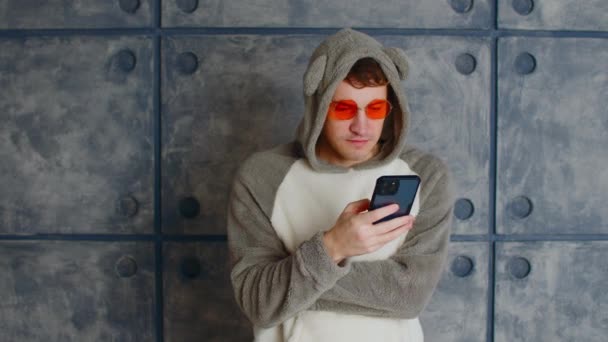 Kigurumi Güneş Gözlüklü Adam Akıllı Telefon Kullanıyor Kapüşonlu Parlak Turuncu — Stok video