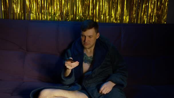 Man Robe Non Working Remote Control Watching Sitting Sofa Dark — Stockvideo