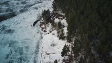 Soğuk kış gününde buzla kaplı sakin, donmuş bir nehir. Huzurlu nehir suyu ve karlı sahil soğuk gri bir günde kırsal kesimde